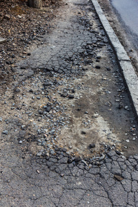 因雨雪损坏的坏道路需要修理。 破碎的沥青涂层会导致车辆和行人的坑洞危险。 糟糕的紧急道路。 危险的道路。 大裂缝破坏道路