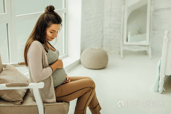 年轻的三三个月孕妇触摸她的肚子