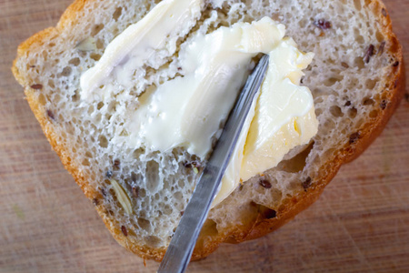用餐刀把黄油涂在面包上图片