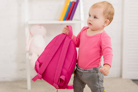 穿粉色衬衫的可爱孩子，带着粉红色的包在儿童房