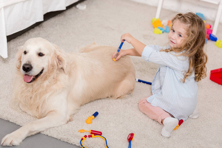 儿童房中可爱儿童假装兽医和检查金毛猎犬的高角度视角