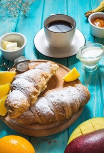 早餐提供咖啡橙汁牛角面包和蓝木色背景水果