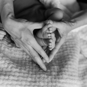 老式的色调关闭母亲的手，抱着新生的婴儿脚的声音形状。 可爱的小男孩脚趾宏观照片与毛绒衬里舒适的毛毯背景