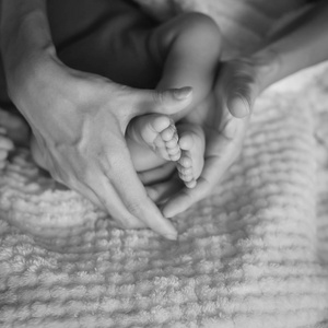 老式的色调关闭母亲的手，抱着新生的婴儿脚的声音形状。 可爱的小男孩脚趾宏观照片与毛绒衬里舒适的毛毯背景