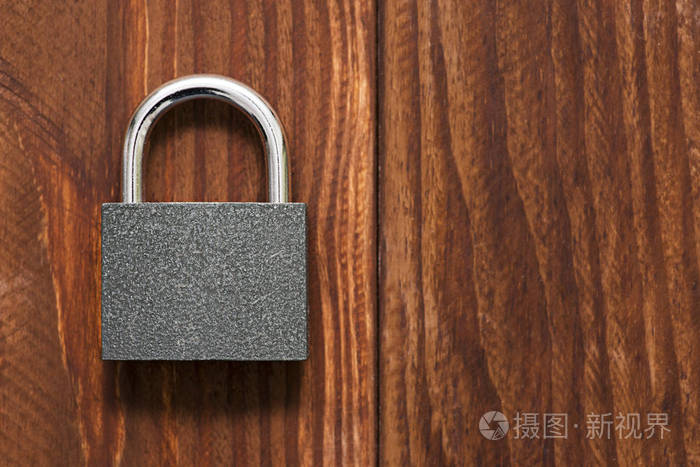 木制背景上的安全挂锁. 检查棕色木桌背景上的锁