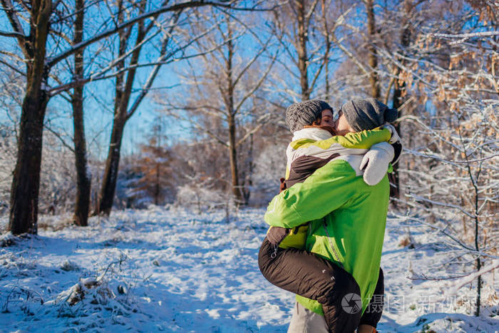 幸福的一对相爱的夫妇在冬天的森林里散步和拥抱男人抱着女朋友接吻