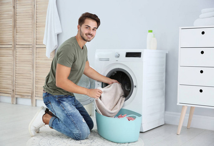 年轻人在家里用洗衣机。 洗衣日