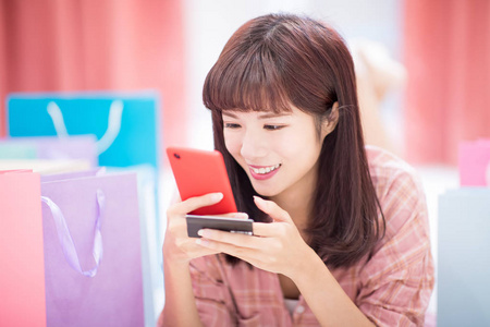年轻女子在网上购物，家里带着智能手机