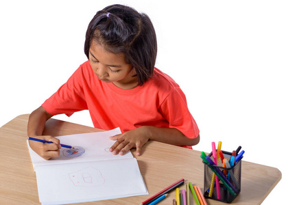 可爱开朗的孩子用彩色铅笔画画，而坐在桌子上，孤立在白色背景上，有剪裁的路径。 家庭教育