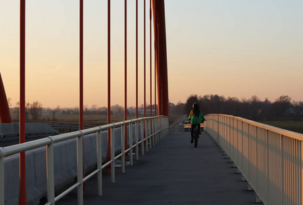 波兰9，9，2018年高速公路上悬挂的路桥。 金属建筑技术结构。 现代建筑。 那个女孩晚上骑自行车过桥。