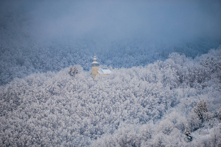 雪覆盖森林树木和景观与教堂在阿尔卑斯山