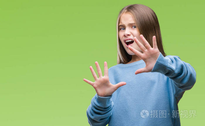 年轻漂亮的女孩穿着冬天的毛衣,在孤立的背景下害怕和恐惧,表情停止用