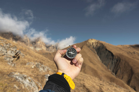 一名男性徒步者正在寻找秋天山区有磁罗盘的方向.视点拍摄.
