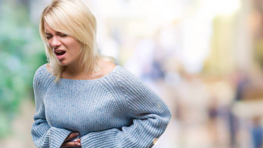 着冬天的毛衣,在孤立的背景上,手放在肚子上,因为消化不良,痛苦的疾病