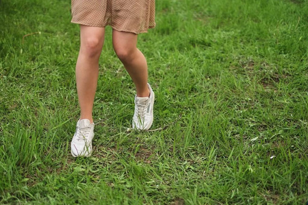 穿着白色运动鞋和裙子的女人在绿草上奔跑照片