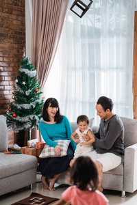 幸福家庭的肖像坐在圣诞节旁边的沙发上