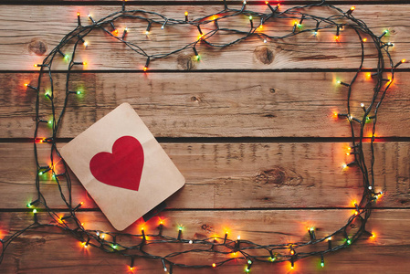 s Day. Card with a red heart framed by a Christmas garland on a 