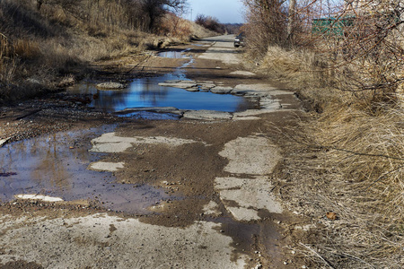 非常糟糕的铺路。 路面坑洞的裂缝。 低质量修补后局部沥青道路状况极差