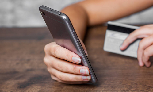 s hands holding a credit card and using smartphone for online sh