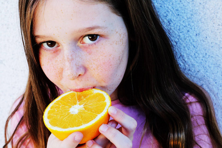 十几岁的女孩在户外拿着橙色的新鲜水果