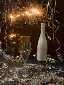 新年背景，在玻璃和香槟瓶中燃烧的火花，背景上有圣诞物品