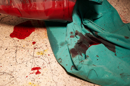 手术后有血迹和缝线的肮脏地板.塑料袋里装满了水和血.