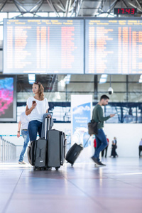 在办理登机手续和登机前的安全检查前，年轻女子带着行李在国际机场