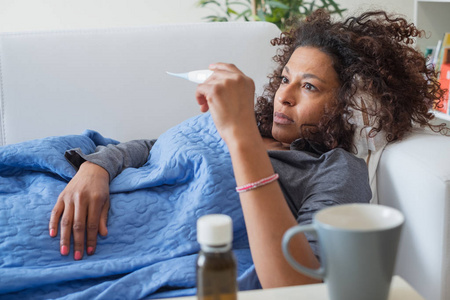 生病的黑人妇女检查温度计和季节性流感