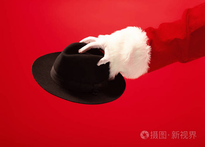 圣诞老人手拿着一顶男性帽子在红色背景