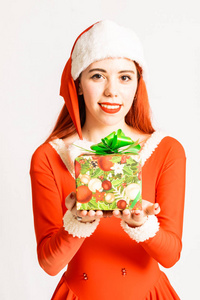 年轻漂亮的红头女孩穿着圣诞老人迷你裙，穿着中性的白色背景，带着礼物