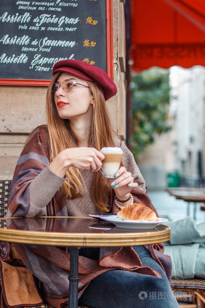 美丽的女孩早上在巴黎的咖啡馆喝咖啡