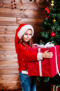 圣诞快乐, 节日快乐。可爱的小女孩与大红色礼物礼物礼物礼物箱子在树附近室内