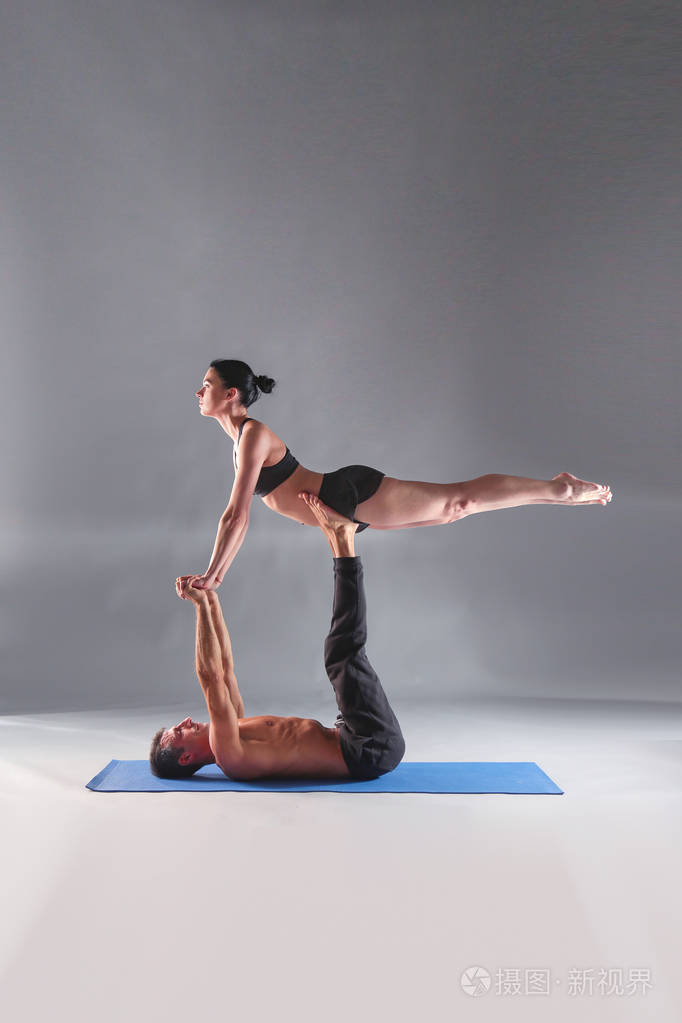 年轻夫妇一起练习杂技瑜伽工作室在垫子上杂技几个瑜伽双人瑜伽