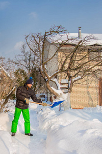 一个人在一个阳光明媚的冬日打扫他家附近的院子和雪园。