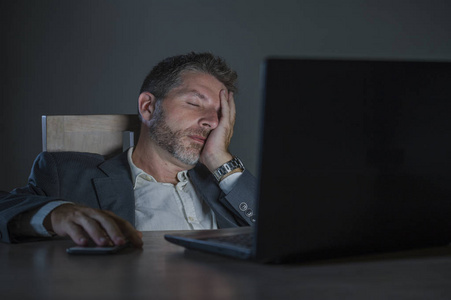 的,疲惫不堪的企业家,一个深夜在办公室笔记本电脑桌上工作的年轻人