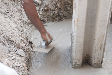 建筑工人在施工现场摊铺湿混凝土。
