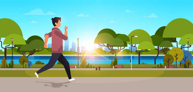 年轻人慢跑户外现代公共公园家伙在耳机运行体育活动概念城市景观日落背景水平横幅平