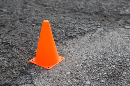 灰色沥青上的塑料橙色路锥.照片