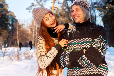 美丽的国际情侣捧着雪花，在雪地上的冬天在公园里微笑..