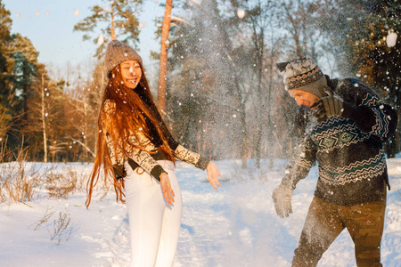 美丽的国际情侣捧着雪花，在雪地上的冬天在公园里微笑..