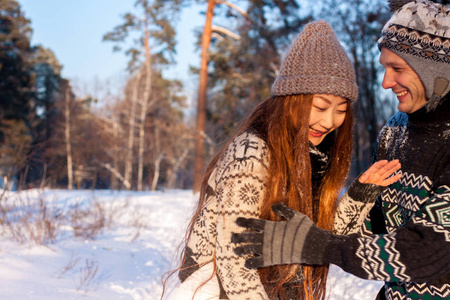 美丽的国际情侣捧着雪花，在雪地上的冬天在公园里微笑..