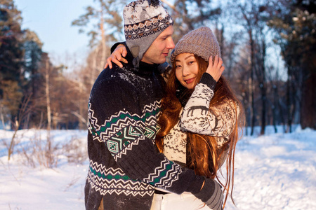 美丽的国际夫妇拿着雪花，在冬天的雪上在公园里微笑。