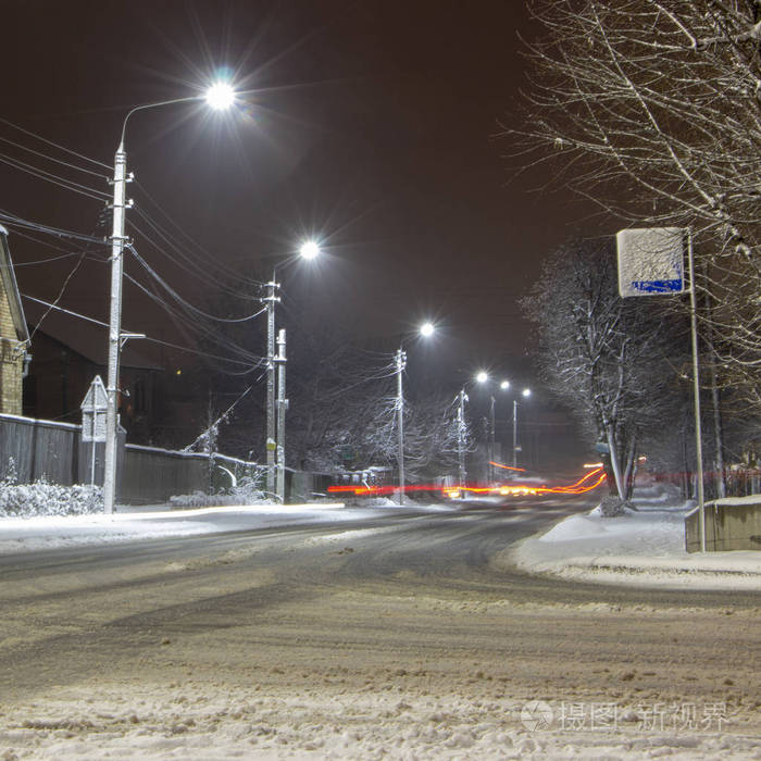 美丽的乡村冬天，雪覆盖着街上挂着灯笼。 汽车背景的灯光轨迹