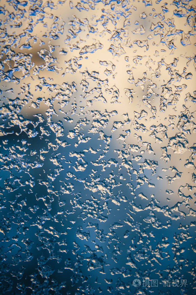 冰冻的冬天窗户上的图案,有清晨的阳光.玻璃上的冰. 玻璃上的冰背景.