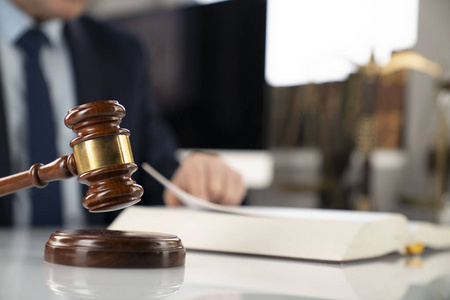 律师概念背景. 在办公室工作的律师. 白色玻璃桌子上的木槌和法律书.