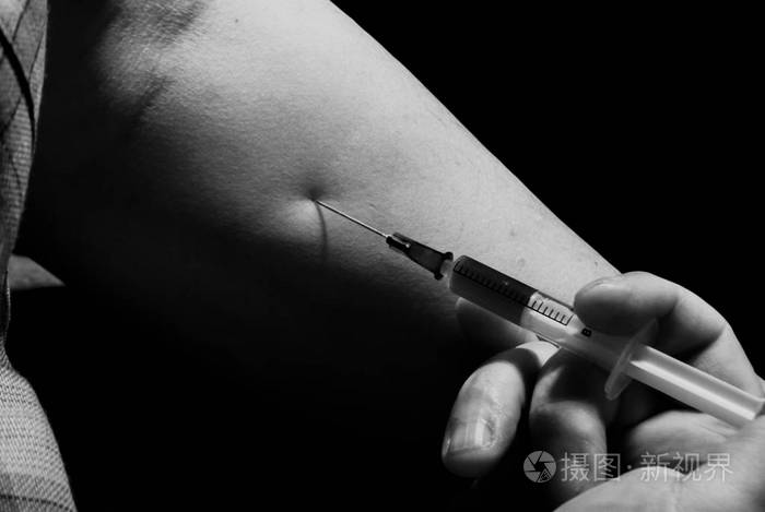 药物注射器在黑暗背景下向血液静脉注射针头