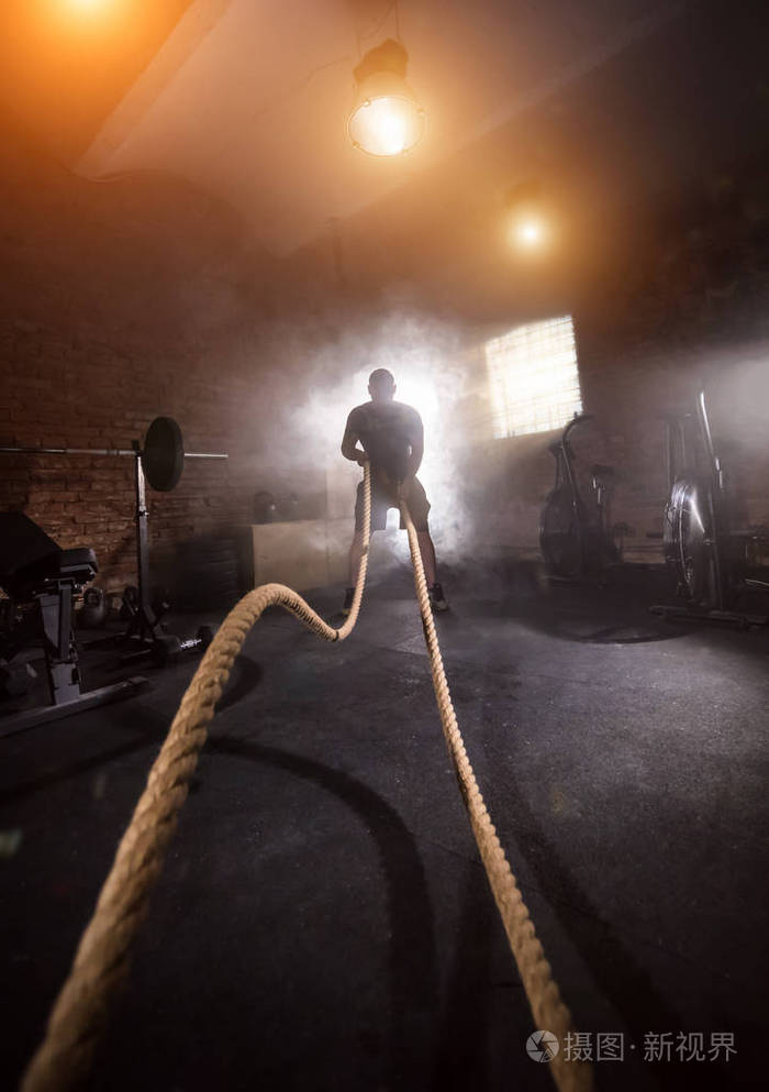 年轻人在健身房内部做艰苦的锻炼用绳子挥动电影情绪