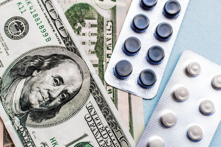 蓝色背景下美元钱上的药丸。 医药费用。 高成本的药物概念。