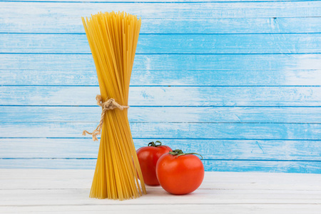 新鲜美味的意大利意大利面意大利通心粉潮天然助熔剂生物有机新鲜西红柿白色和蓝色木制纹理的旧背景
