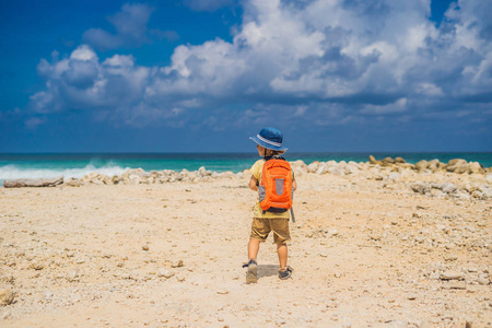 男孩与旅行者背包在惊人的梅拉斯蒂海滩巴厘岛印度尼西亚。